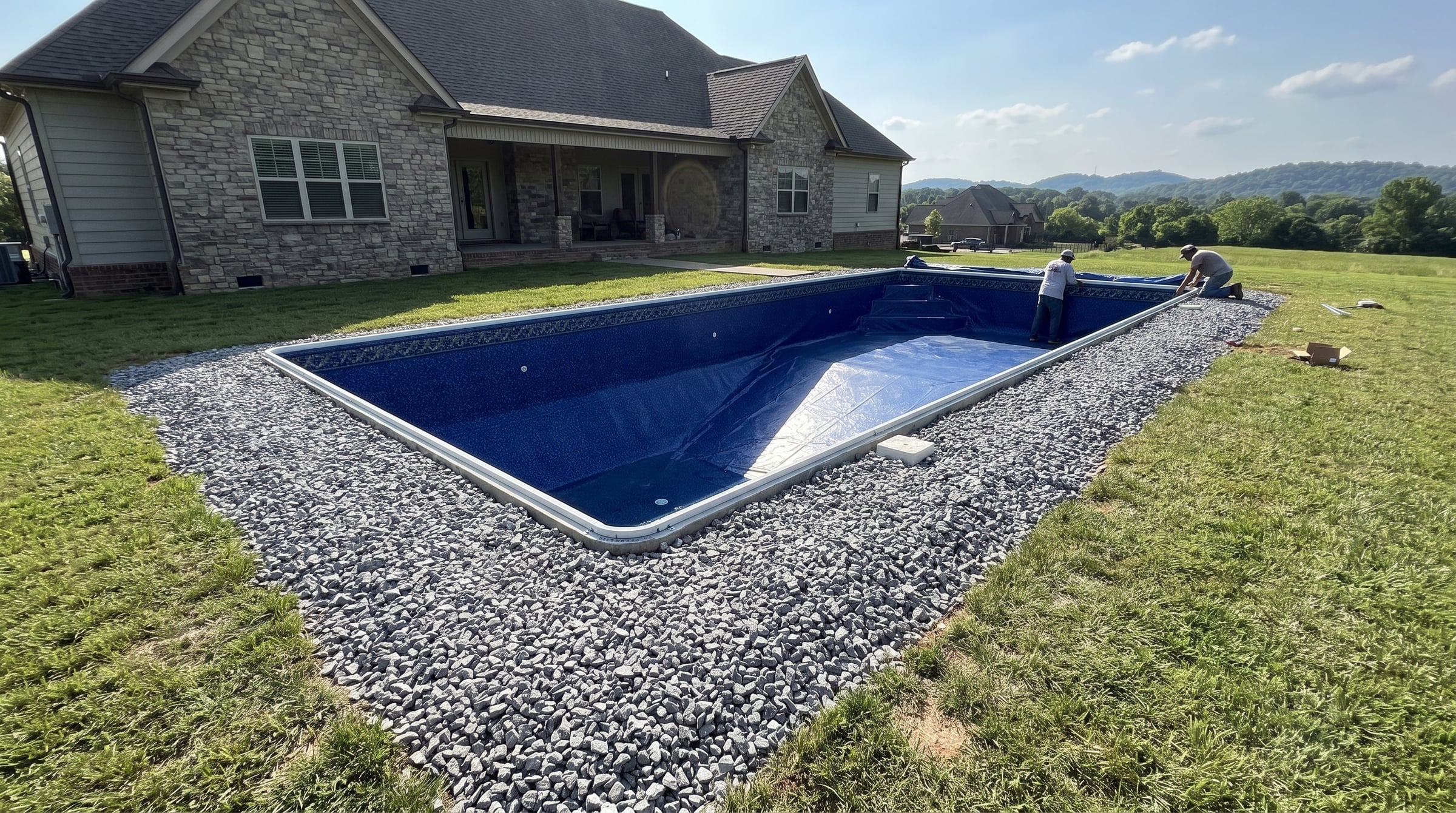 Crew fitting a new blue vinyl liner in a custom pool overlooking the hills