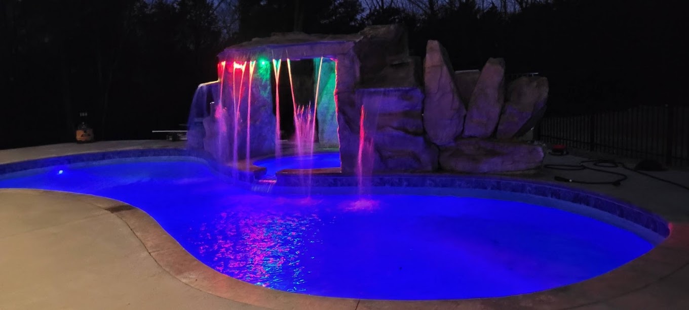 Pool lit blue with color LED lighting and lit waterfalls after dark