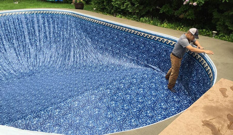 Installer fitting a new patterned vinyl liner in a backyard pool