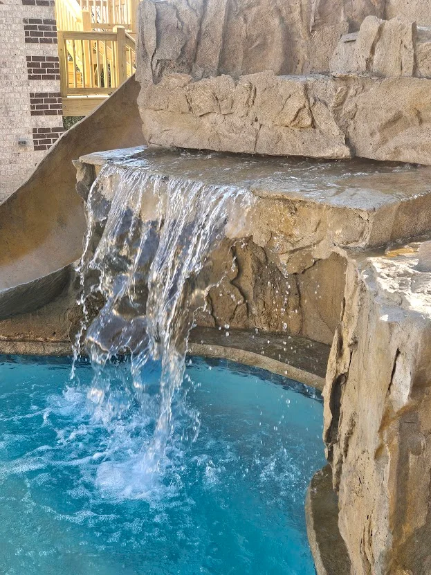 Waterfall spilling into a custom backyard pool