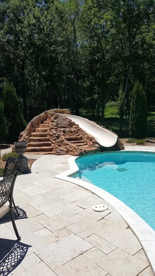 Rock waterslide into a backyard resort pool